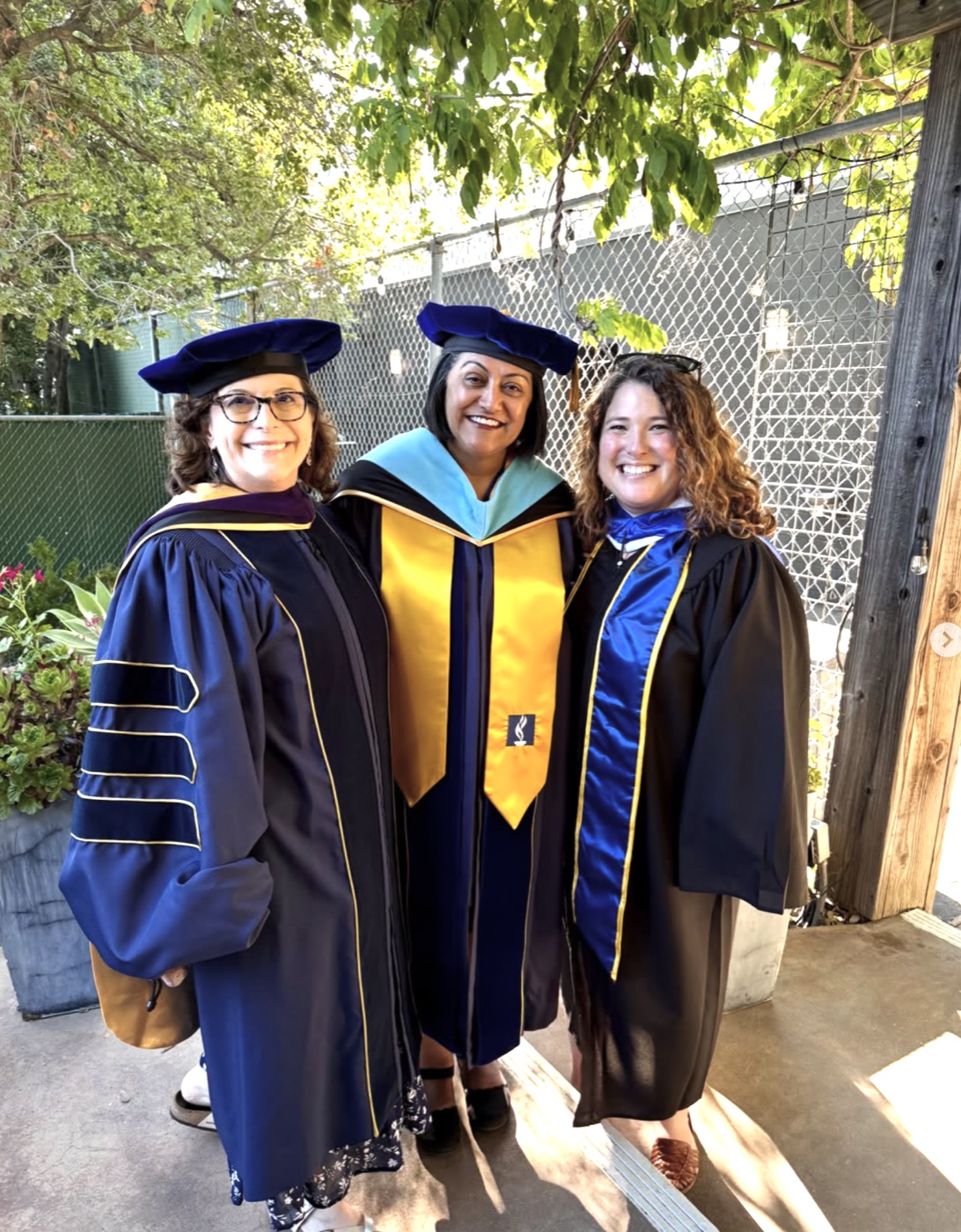 Rebecca Barrett in academic regalia with two colleagues at a graduation ceremony
